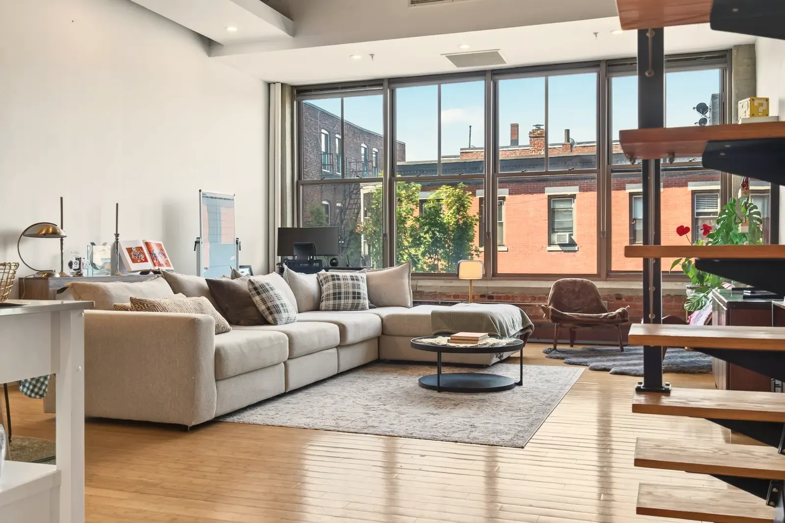 A loft living room whose narrow wood strips run toward a wall of large windows