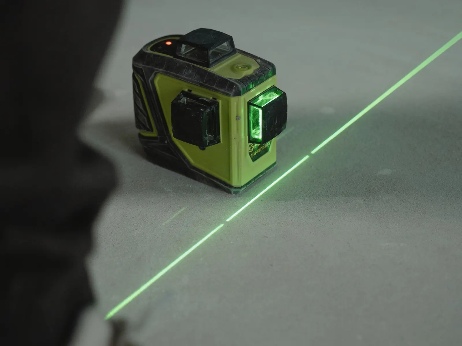 Una livella laser a linee proietta una linea verde dritta di riferimento sul massetto nudo