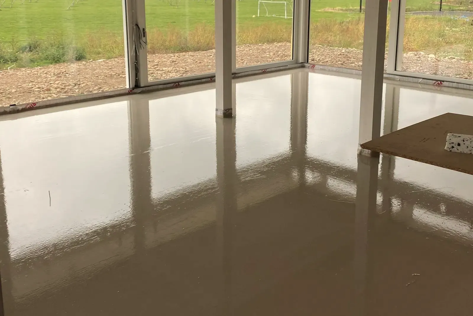 A freshly poured, glossy, flat floor in an empty room with large windows