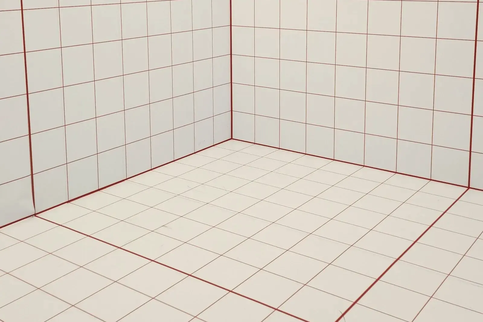 A small room with white wall and floor tiles and contrasting red grout lines, showing an even joint grid