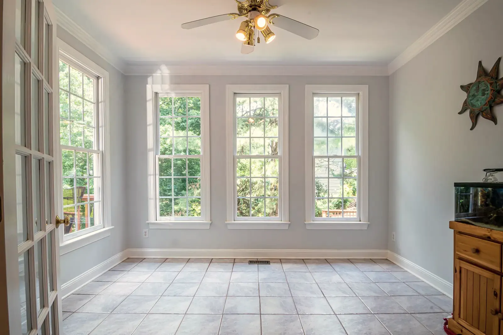 Bright empty room with a gray tile floor laid in a straight grid below tall windows