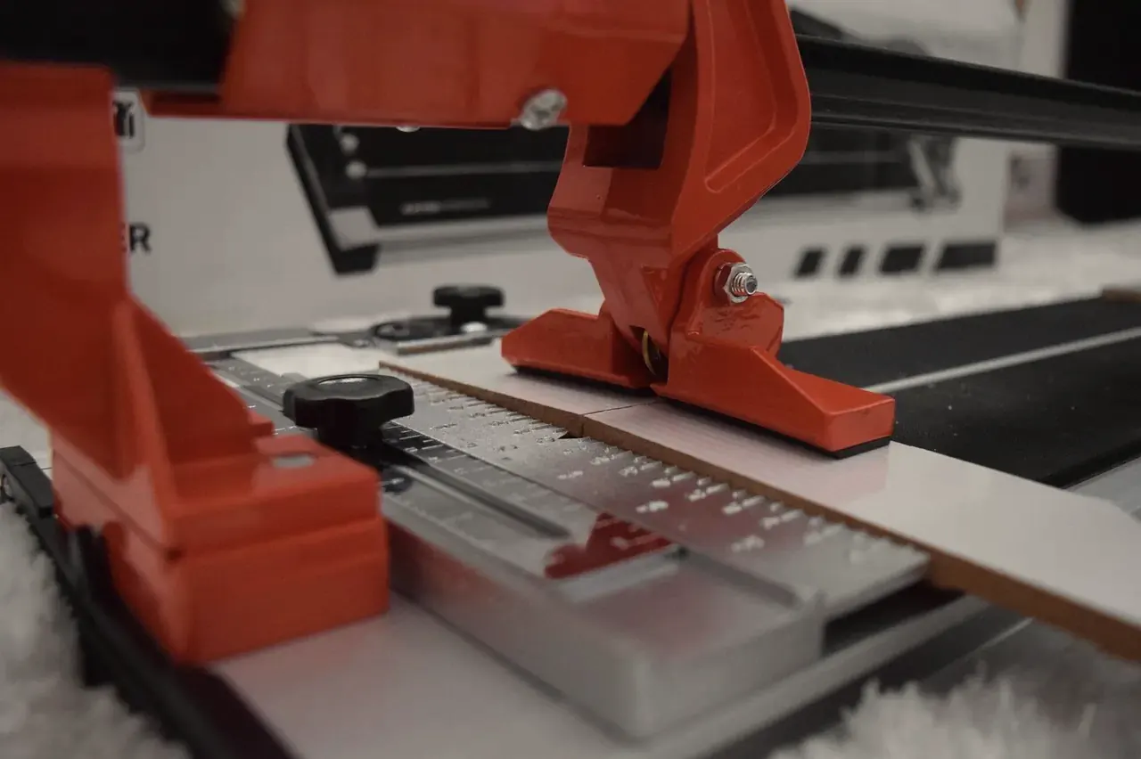 Manual tile cutter scoring a strip of ceramic tile along its measuring guide