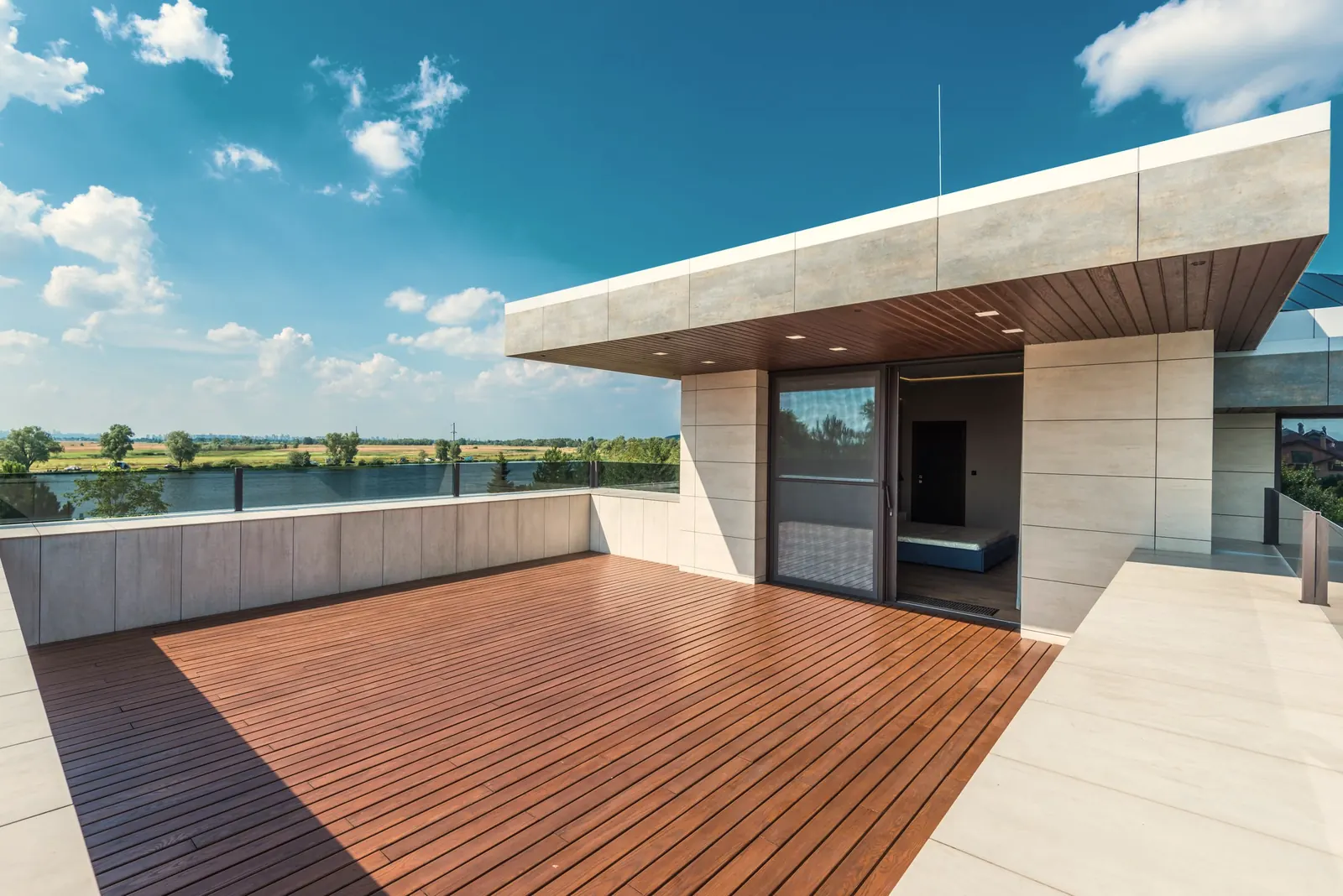 Finished roof terrace of warm brown wooden boards in long parallel rows with even gaps, in front of a glass wall