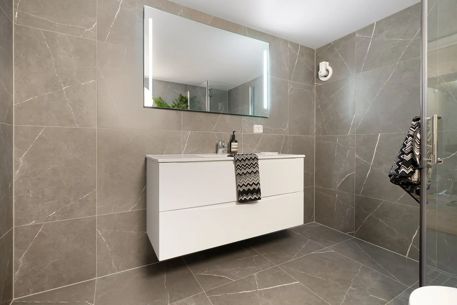 Small bathroom with large grey stone-look tiles in a straight grid