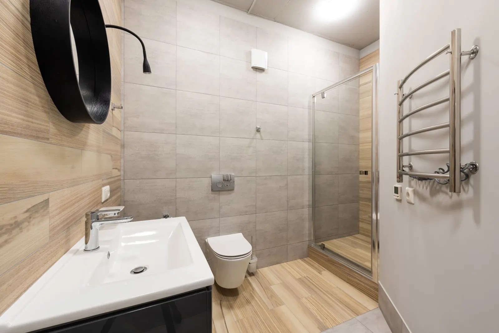 Small bathroom with a wood-look plank floor and grey wall tiles