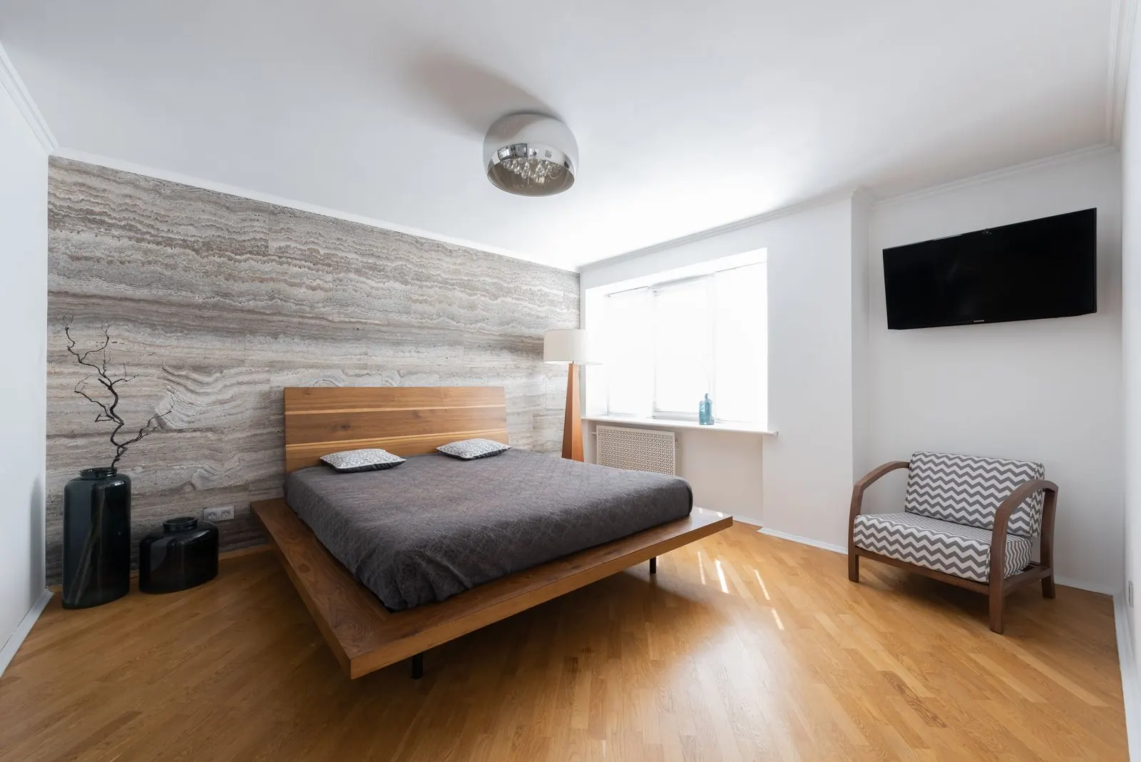Bedroom with a natural oak plank floor and a wooden bed