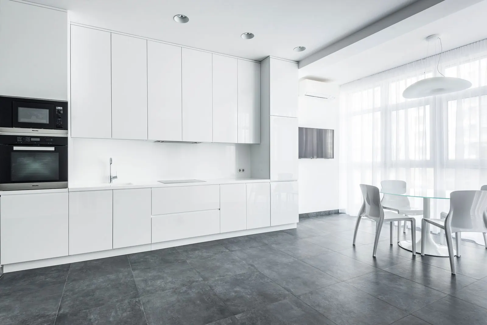 White kitchen with large dark grey floor tiles in a straight grid