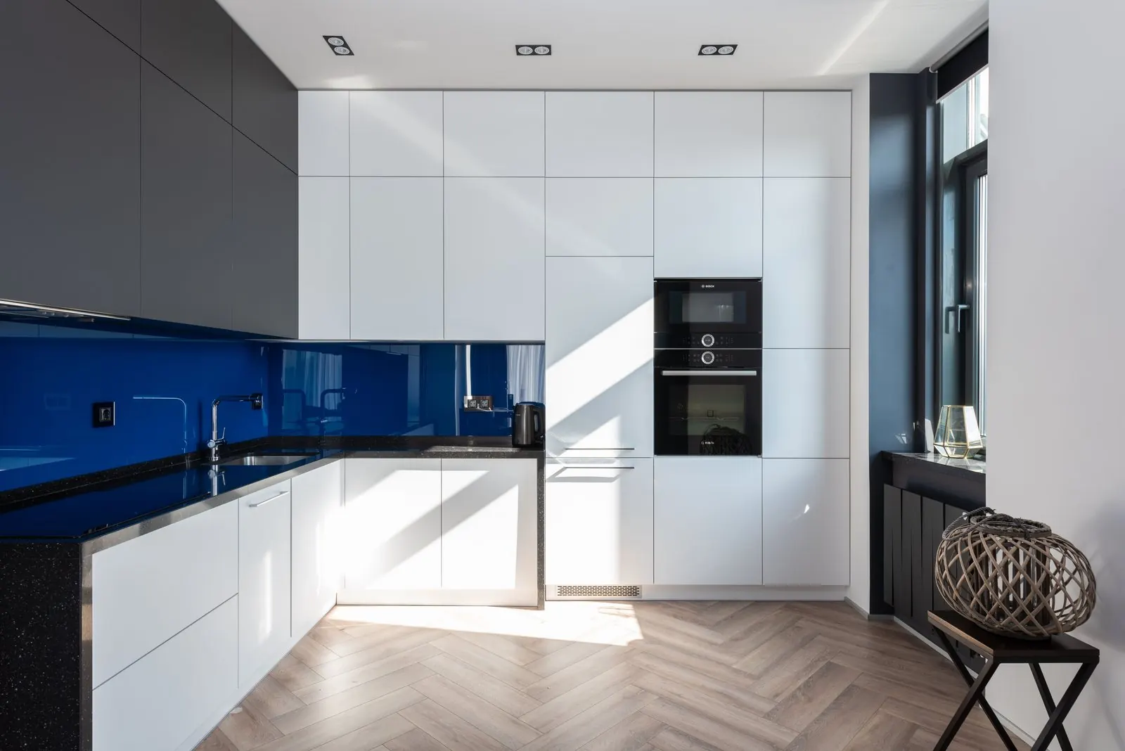 Modern white kitchen with a light wood-look herringbone floor