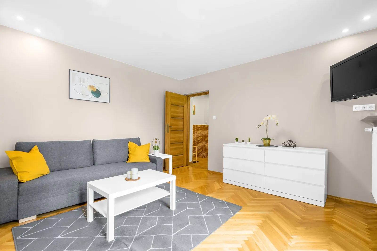 Living room with an oak herringbone parquet floor, grey sofa and white sideboard