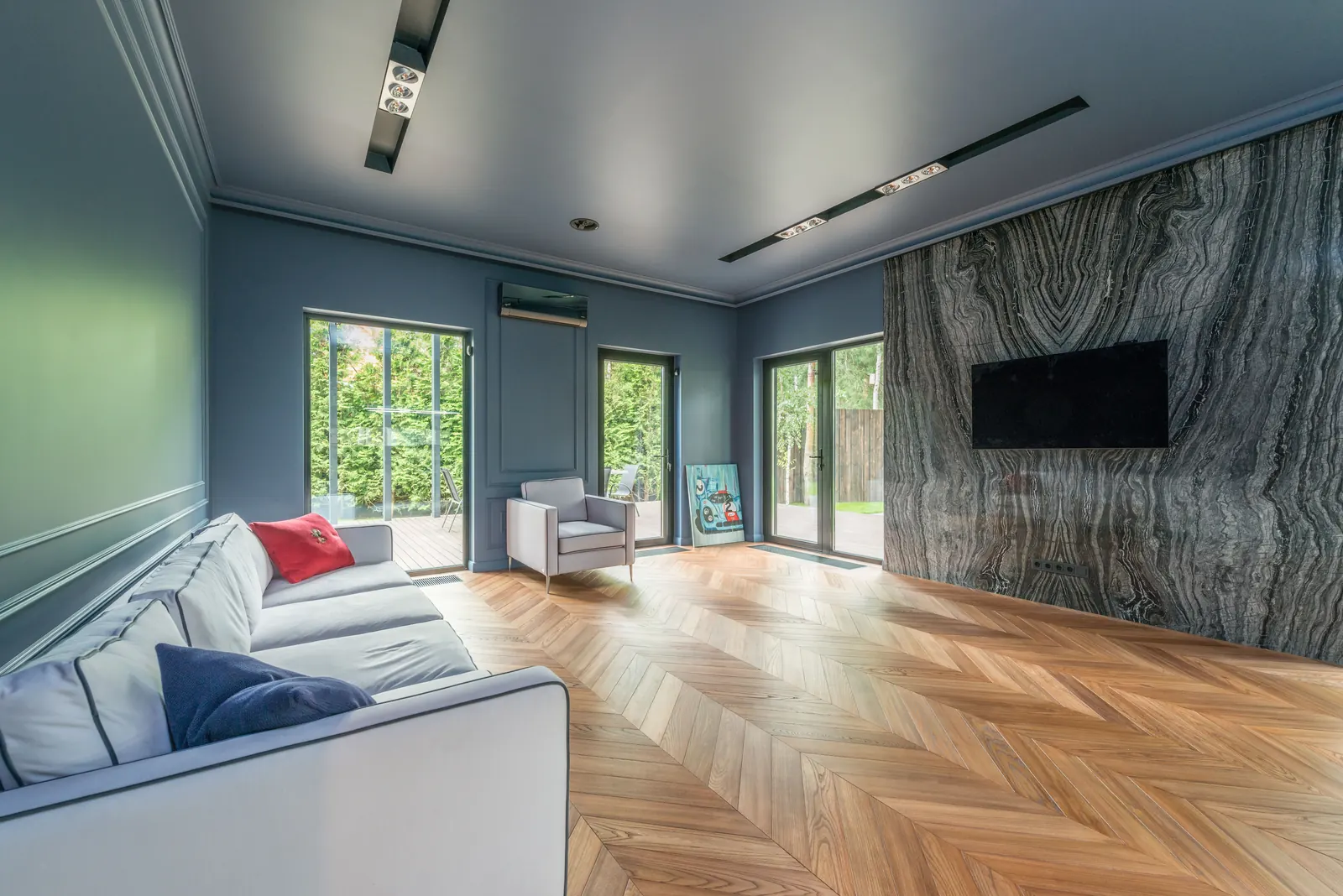 Living room with a natural oak chevron parquet floor, light sofa and garden doors
