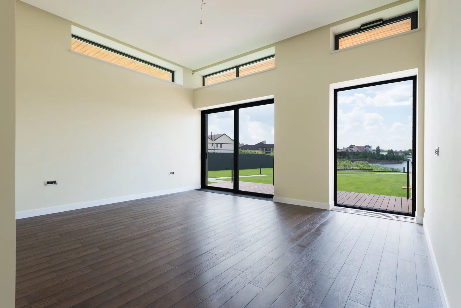 Empty living room with dark wood-look laminate and glass doors to the garden