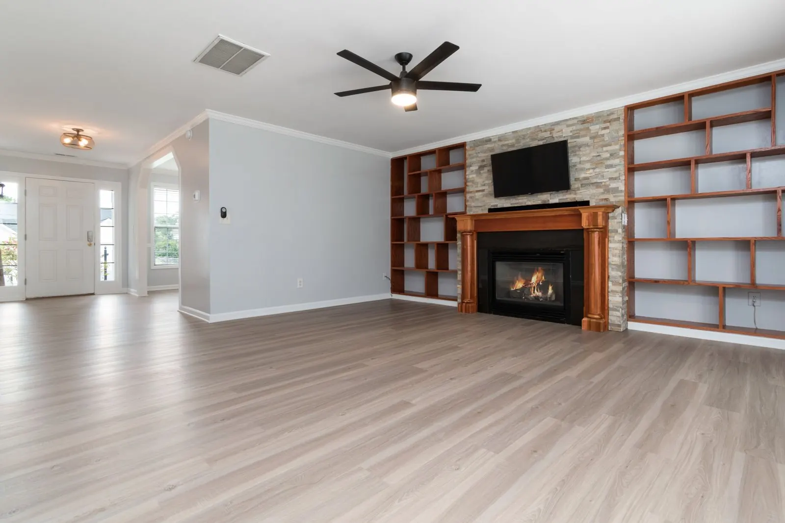 Empty living room with light grey wood-look vinyl planks and a fireplace