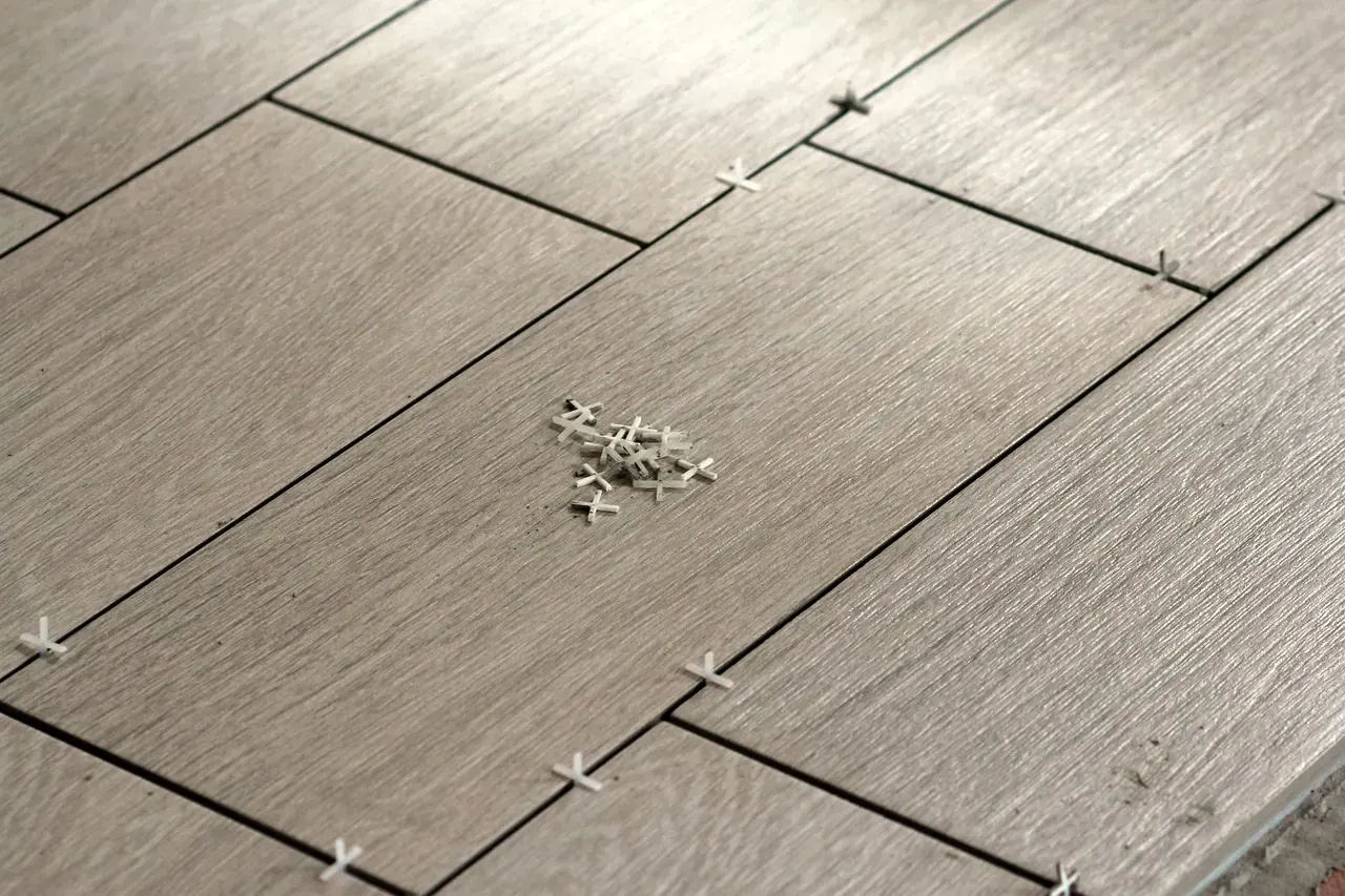 Freshly laid wood-look floor tiles with tile spacers in the open joints, ready for grouting