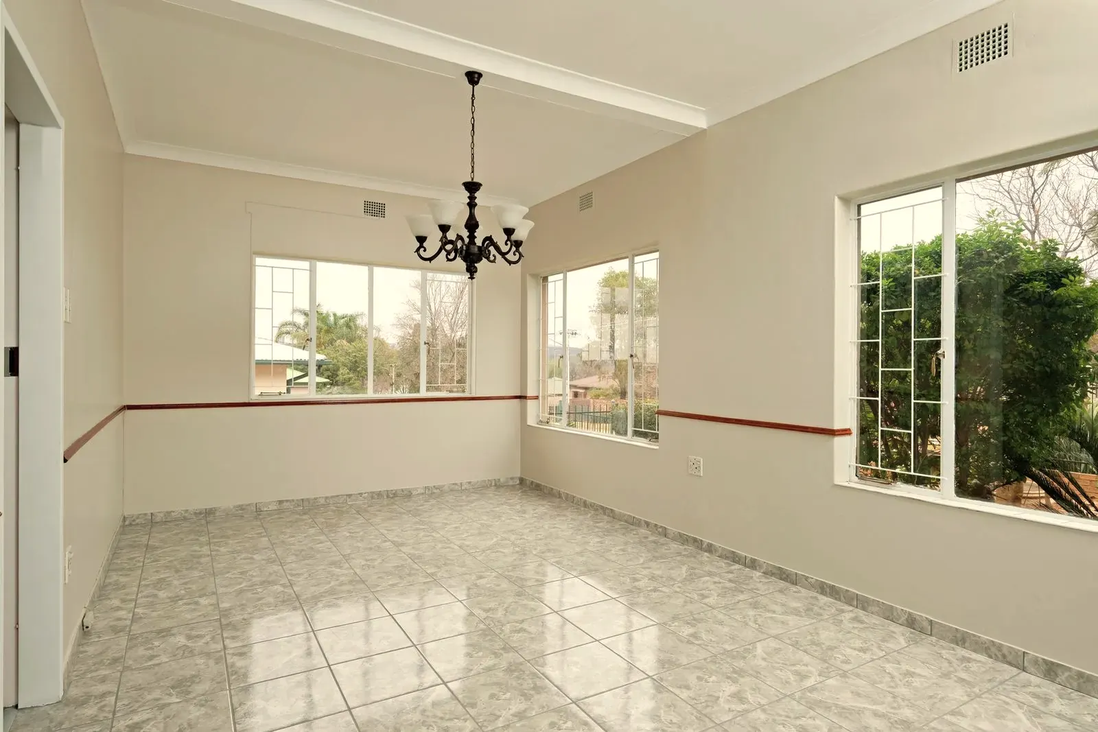 Una habitación vacía y limpia con un suelo de baldosa cerámica gris efecto mármol algo antiguo, lista para la reforma
