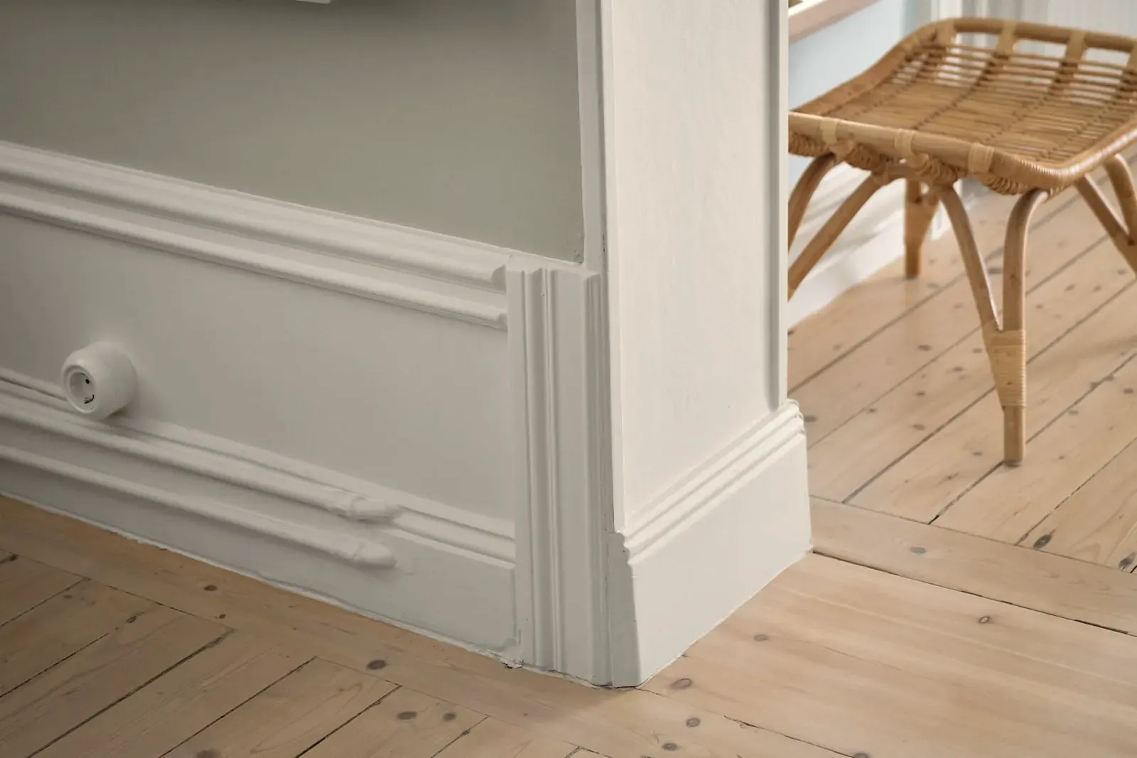 Gros plan sur une plinthe blanche posée et son angle sur un plancher